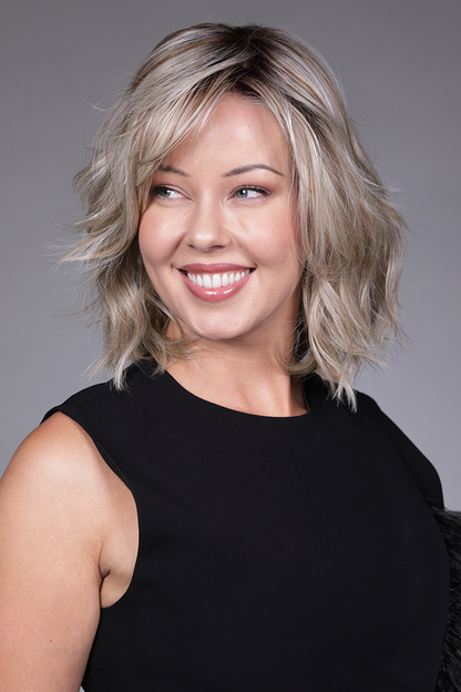 Donna by Belle Tress in Butterbeer R 10/60/88+8 | Butterbeer Root hair color is an inviting blend that exudes a cozy, radiant charm. The roots feature soft dimensions of brown base with a touch of depth, giving a natural and lived-in look. This transitions smoothly into a buttery blonde, infused with creamy honey and toffee tones that shimmer like the frothy top of a freshly poured butterbeer.